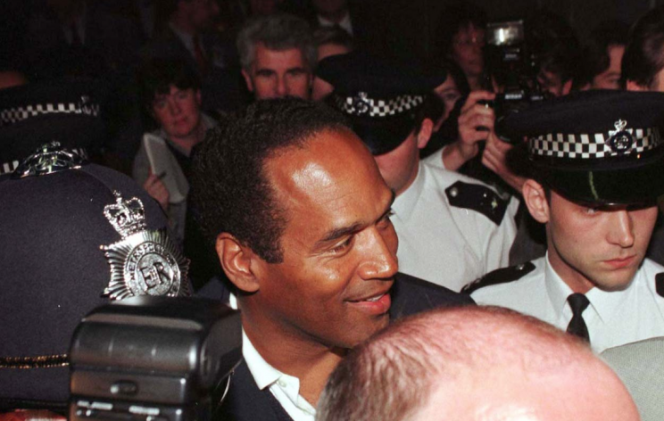 OJ Simpson is surrounded by police and the media at Heathrow airport, on the first day of his visit to London, 1996
