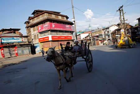A Kashmiri man rides a horse-drawn cart on a deserted road during restrictions after scrapping of the special constitutional status for Kashmir by the Indian government, in Srinagar