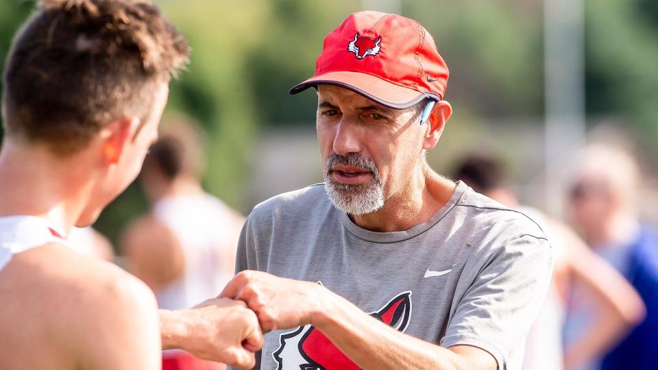Longtime Marist College track and field coach Pete Colaizzo exchanges a fist bump with one of his athletes.