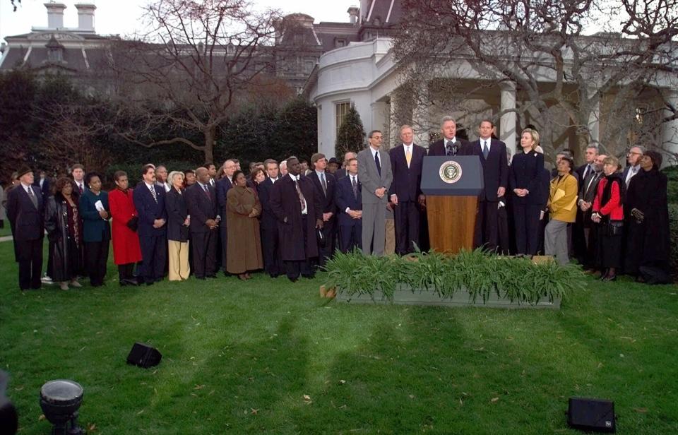 FILE - In this Dec. 19, 1998, file photo, then-President Bill Clinton is joined by Democratic lawmakers and aides outside the Oval Office of the White House in Washington, after the House of Representatives voted to impeach the president. Twenty-one years ago this Thursday, a Republican-led House voted to impeach then-President Bill Clinton. While that battle was bitterly partisan, it was blurrier than the clean, near party-line votes expected this week when the chamber _ now run by Democrats _ is poised to impeach President Donald Trump. (AP Photo/Doug Mills, File)