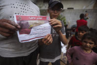 Palestinians hold leaflets dropped by Israeli planes calling on them to evacuate ahead of an Israeli military operation in Rafah, southern Gaza Strip, Monday, May 6, 2024. The order affects tens of thousands of people and could signal a broader invasion of Rafah, which Israel has identified as Hamas' last major stronghold after seven months of war. (AP Photo/Ismael Abu Dayyah)