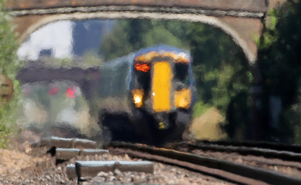 A train moves through heat haze in Ashford, Kent, as the continued hot weather causes problems across the rail network.