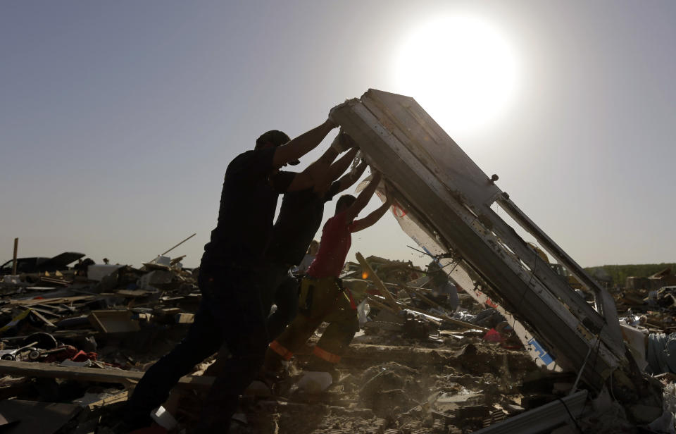 Workers flip a fallen wall as they search through homes destroyed by a tornado, Monday, April 28, 2014, in Vilonia, Ark. Arkansas Gov. A dangerous storm system that spawned a chain of deadly tornadoes killed dozens from the Midwest to the Deep South. (AP Photo/Eric Gay)