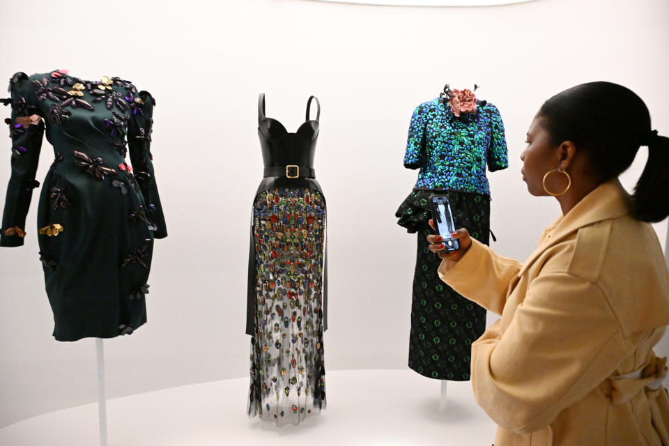 Woman observing three mannequins with elegant dresses in a display