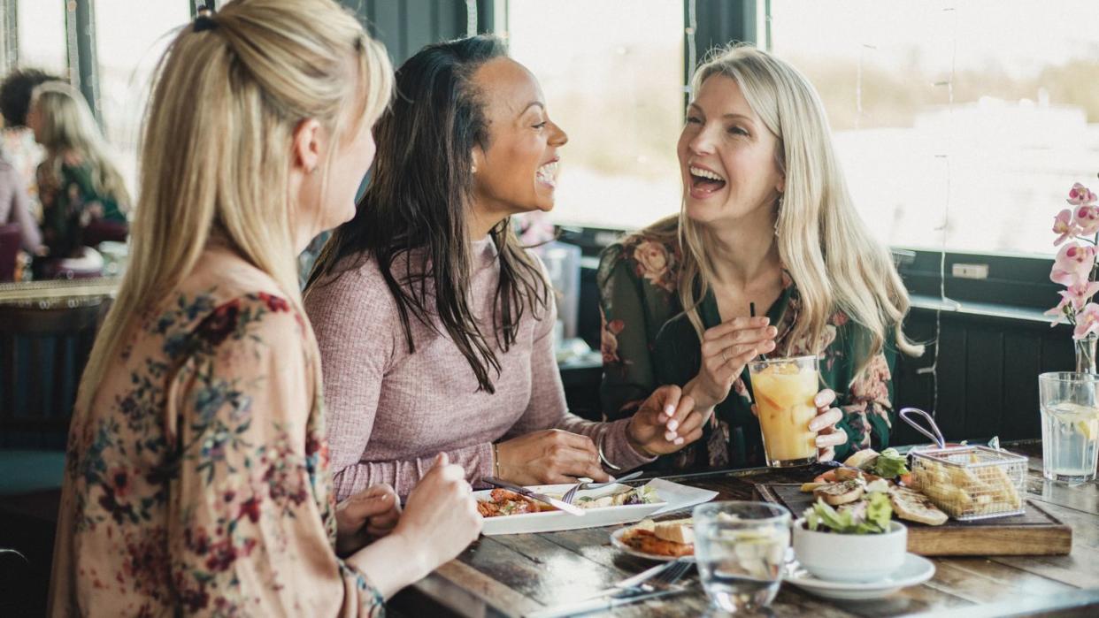 a front view shot of three mid adult women enjoying brunch together in a restaurant