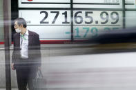 A person stands in front of an electronic stock board showing Japan's Nikkei 225 index at a securities firm as a vehicle passing by Friday, Oct. 28, 2022, in Tokyo. Shares were mostly lower in Asia on Friday after a mixed session on Wall Street, where tech sector losses offset gains in other parts of the market. (AP Photo/Eugene Hoshiko)