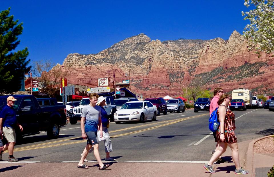 Shoppers cross a street in uptown Sedona. There, roads and sidewalks often bustle with visitors buying, eating and pampering themselves at higher-end businesses typically staffed by people whose limited salaries make it impossible for them to afford housing in the area.