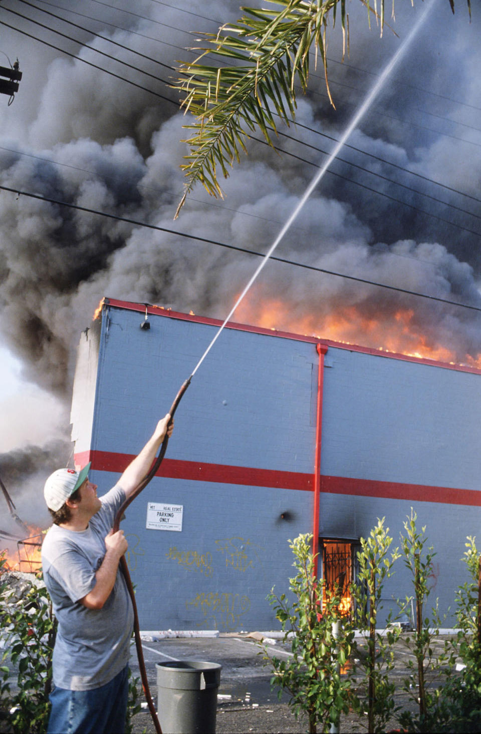 Man spraying water on burning building