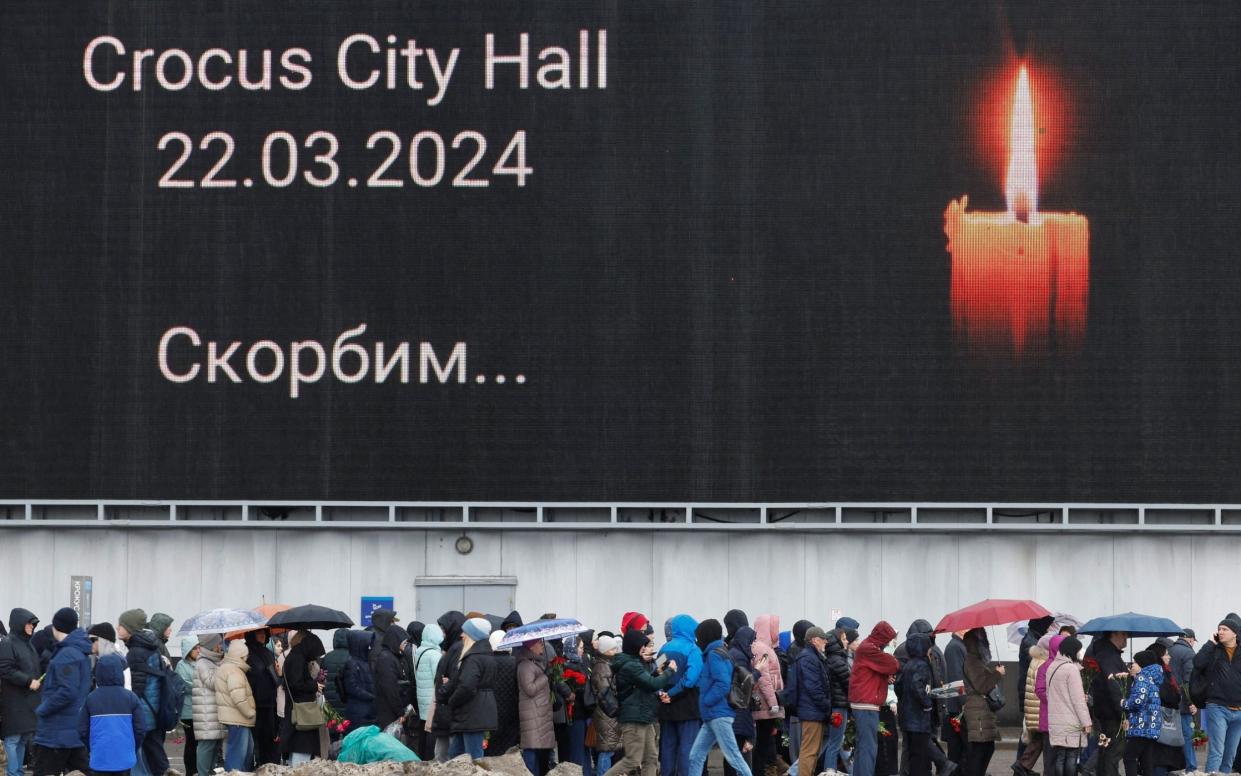 People line up to lay flowers at a makeshift memorial to the victims of a shooting attack set up outside the Crocus City Hall concert venue in the Moscow Region, Russia.