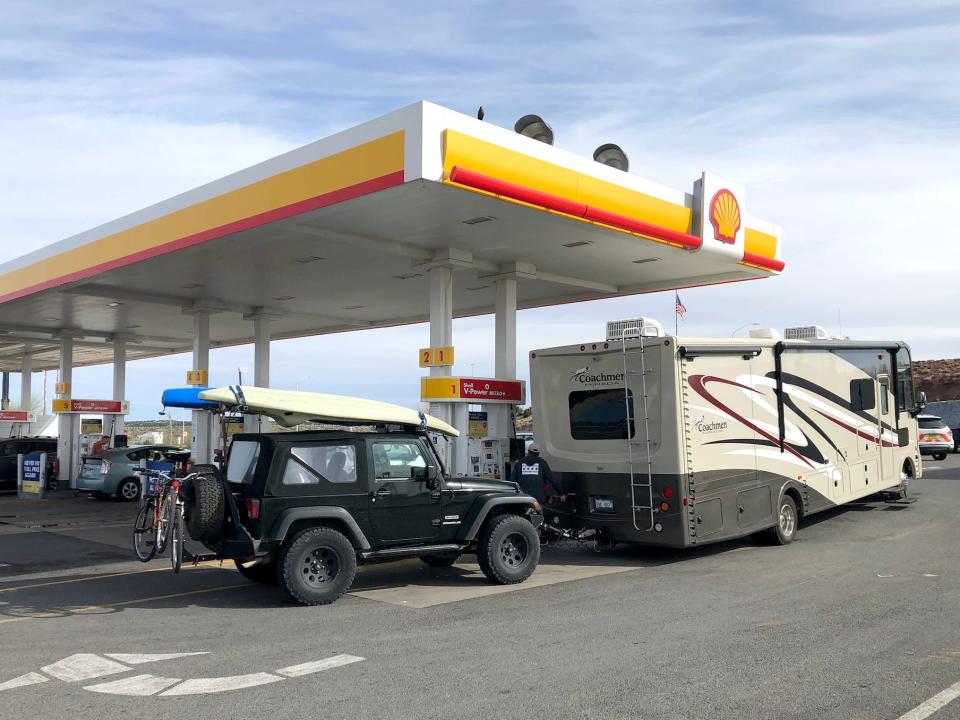 A recreational vehicle stops for gas and is fully prepared for a road trip with an RV, Jeep, Kayak and bicycles April 4 2019, Kingman, Arizona