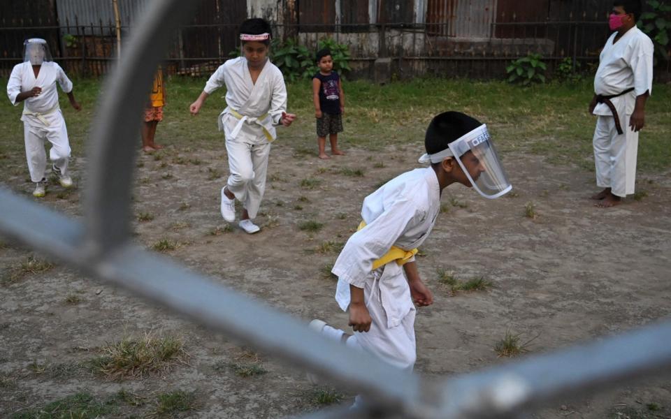Children wearing protective face-shields warm up during a martial arts training class - DIBYANGSHU SARKAR/AFP