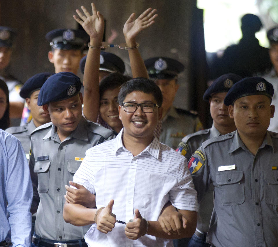 In this Monday, Aug. 27, 2018, file photo, two Reuters journalists Wa Lone, center, and Kyaw Soe Oo, center back, gestures while being escorted by police upon arrival at a court in Yangon, Myanmar. The Myanmar court delayed the verdict against two Reuters journalists on the charge of possessing official documents illegally in a case that has drawn attention to the faltering state of press freedom in the troubled Southeast Asian nation. The verdict that was to be delivered Monday was postponed to Sept. 3. (AP Photo/Thein Zaw, File)