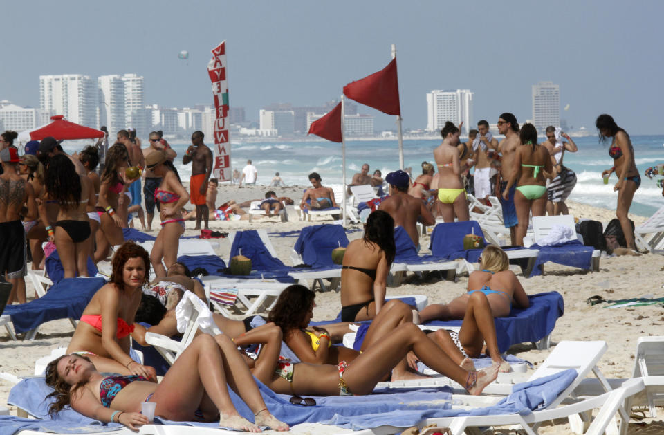 ARCHIVO- En esta fotografía del 10 de marzo de 2012 se muestran vacacionistas en la playa de Cancún, en México. Casi siete millones de turistas de todas partes del mundo visitan esta parte de la costa mexicana al año, muchos de los cuales llegan al aeropuerto de Cancún y viajan por carretera a la Riviera Maya. (AP Foto/Israel Leal, Archivo)