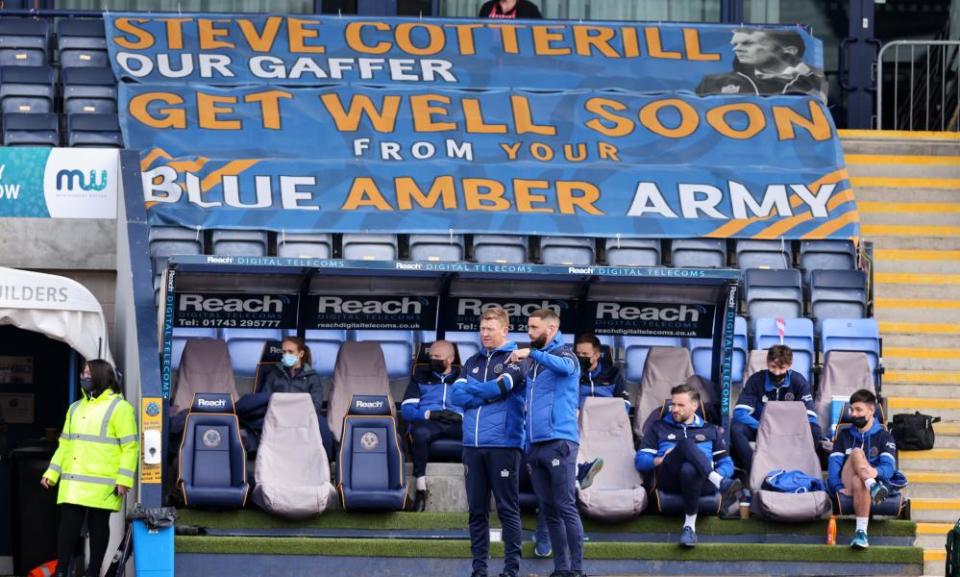 Aaron Wilbraham and David Longwell on the touchline in front of a banner in support of Steve Cotterill, who has spent 49 days in hospital.