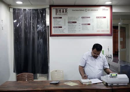 Kishan Singh Bisht, a jail warden in Tihar, maintains a register inside a restaurant run by the Tihar Jail authorities on Jail Road in west Delhi July 21, 2014. REUTERS/Anindito Mukherjee