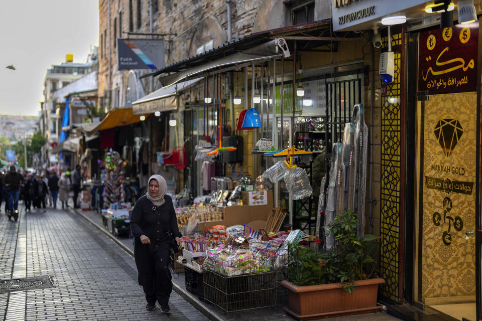 A women walks by a Syrian shop in an outdoor market in Fatih district of Istanbul, Turkey, Tuesday, May 23, 2023. Two opposing visions for Turkey’s future are on the ballot when voters return to the polls Sunday for a runoff presidential election, which will decide between an increasingly authoritarian incumbent President Recep Tayyip Erdogan and challenger Kemal Kilicdaroglu, who has pledged to restore democracy. (AP Photo/Khalil Hamra)