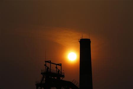 The sun sets behind a chimney of a steel mill in Tangshan, Hebei province February 18, 2014.REUTERS/Petar Kujundzic