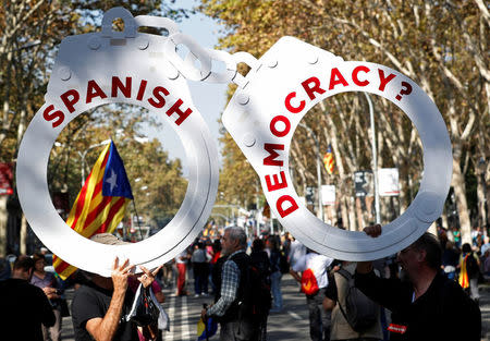 People hold a giant cardboard cut-out of handcuffs during a demonstration outside the Catalan regional parliament in Barcelona, Spain, October 27, 2017. REUTERS/Yves Herman