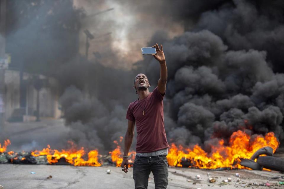 A protester takes a selfie at a burning barricade set by protesters in Port-au-Prince, Haiti, on Monday, Oct. 18, 2021.