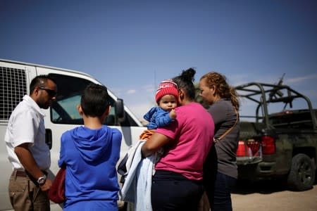 An agent of the National Migration Institute (INM) talks to Honduran migrants after being stopped from crossing the border into the United States by members of the Mexican National Guard, in Ciudad Juarez