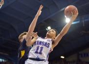 Feb 16, 2019; Lawrence, KS, USA; Kansas Jayhawks guard Devon Dotson (11) shoots as West Virginia Mountaineers forward Logan Routt (31) defends during the second half at Allen Fieldhouse. Mandatory Credit: Denny Medley-USA TODAY Sports