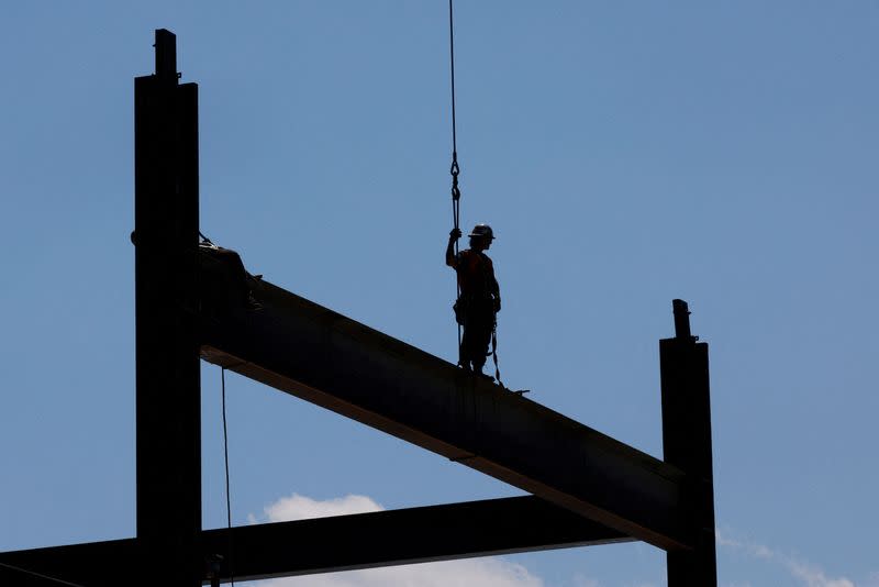 FILE PHOTO: Construction workers install steel beams on high-rise building during a summer heat wave in Boston