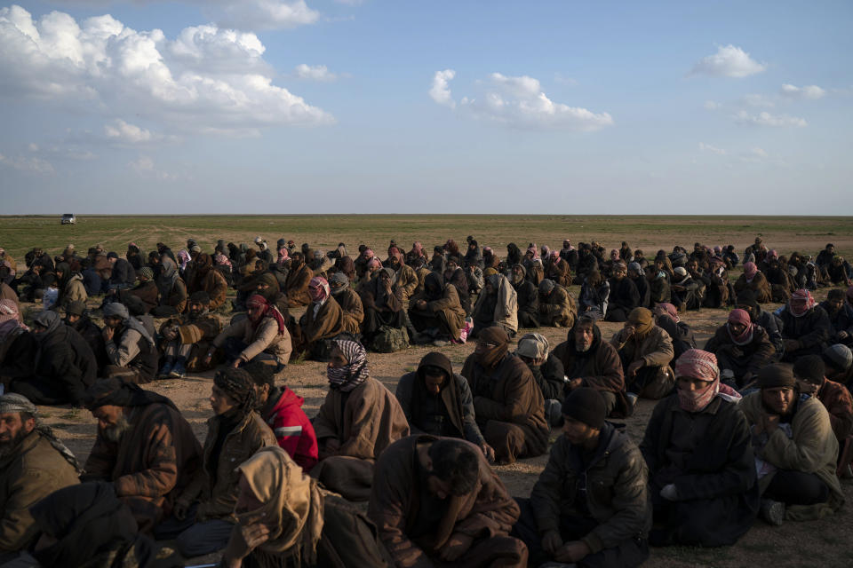 Men wait to be screened by U.S.-backed Syrian Democratic Forces (SDF) fighters after being evacuated out of the last territory held by Islamic State militants, near Baghouz, eastern Syria, Friday, Feb. 22, 2019. (AP Photo/Felipe Dana)