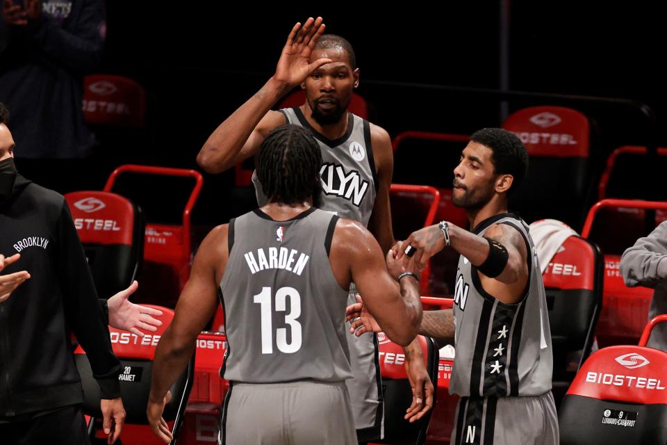 Brooklyn Nets forward Kevin Durant, top center, guard James Harden (13) and guard Kyrie Irving, right, celebrate in the final minute of the second half of an NBA basketball game against the Miami Heat, Monday, Jan. 25, 2021, in New York. (AP Photo/Adam Hunger).