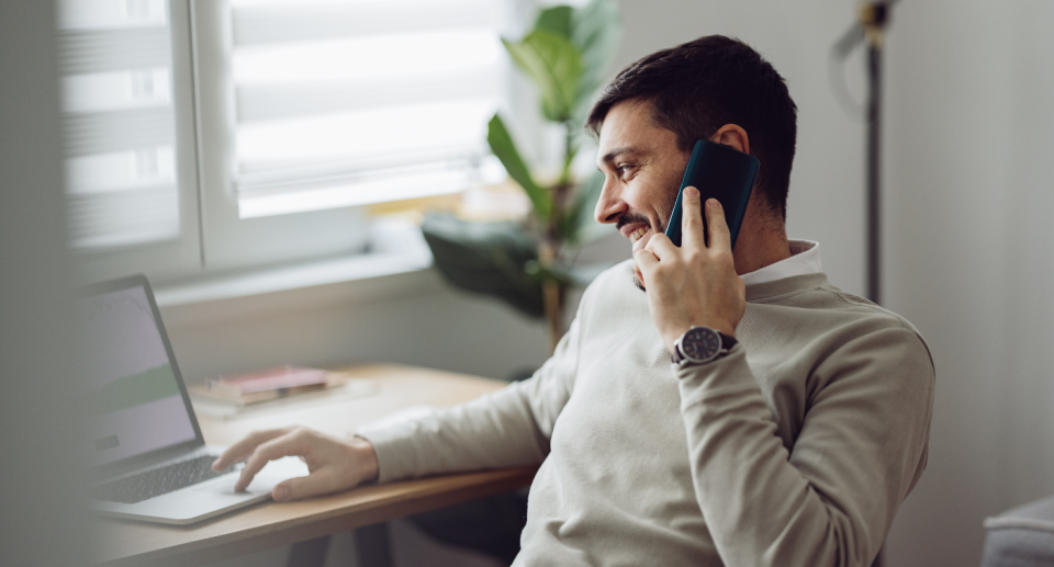 A man talking on the phone as he works from home.