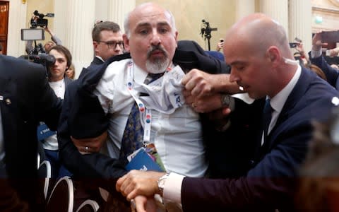 Security staff push out a man after a scuffle prior to a press conference  - Credit: Pablo Martinez Monsivais/AP