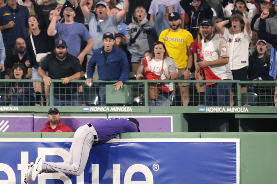 Fans react as Colorado Rockies right fielder Nolan Jones rests on the bullpen wall after making the catch on a deep drive by Boston Red Sox's Rafael Devers during the eighth inning of a baseball game at Fenway Park, Monday, June 12, 2023, in Boston. (AP Photo/Charles Krupa)