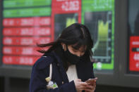 A woman walks by an electronic stock board of a securities firm in Tokyo, Wednesday, Dec. 2, 2020. Asian markets are mixed after the U.S. benchmark S&P 500 set another record. (AP Photo/Koji Sasahara)