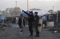 FILE - In this Oct. 27, 2016, file photo, French police officers direct a migrant in the remains of the makeshift migrant camp known as "the jungle" near Calais, northern France. Refugees who stayed at such camps during a 2015 wave of mass migration to Europe have lessons to share with the more than 124,000 people airlifted out of Afghanistan during the U.S.-led evacuation in 2021. (AP Photo/Emilio Morenatti, File)