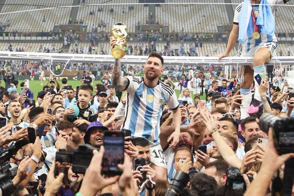Lionel Messi celebrates with teammates while holding aloft the FIFA World Cup Qatar 2022 Winner's Trophy (Lars Baron / Getty Images)
