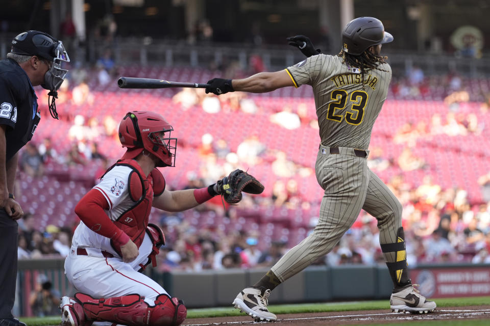 San Diego Padres' Fernando Tatis Jr. singles to left field for his 500th career hit, against the Cincinnati Reds during the first inning of a baseball game Tuesday, May 21, 2024, in Cincinnati. Reds catcher Tyler Stephenson and home plate umpire Hunter Wendelstedt watch. (AP Photo/Carolyn Kaster)