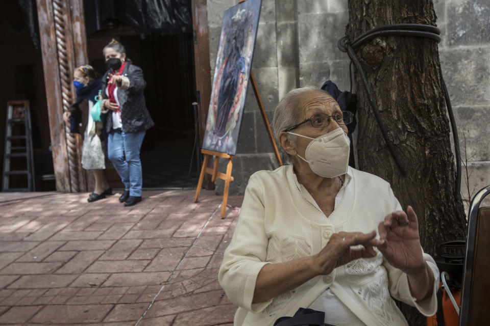 Maria Elena Corona explains how she helped create posters that illustrate the history of Our Lady of the Angels virgin, as she sits outside the quake-damaged Our Lady of the Angels Catholic church, in Mexico City, Sunday, Aug. 7, 2022. Corona, who first set foot in the sanctuary half a century ago, has moved several times since but always found herself drawn to return. (AP Photo/Ginnette Riquelme)