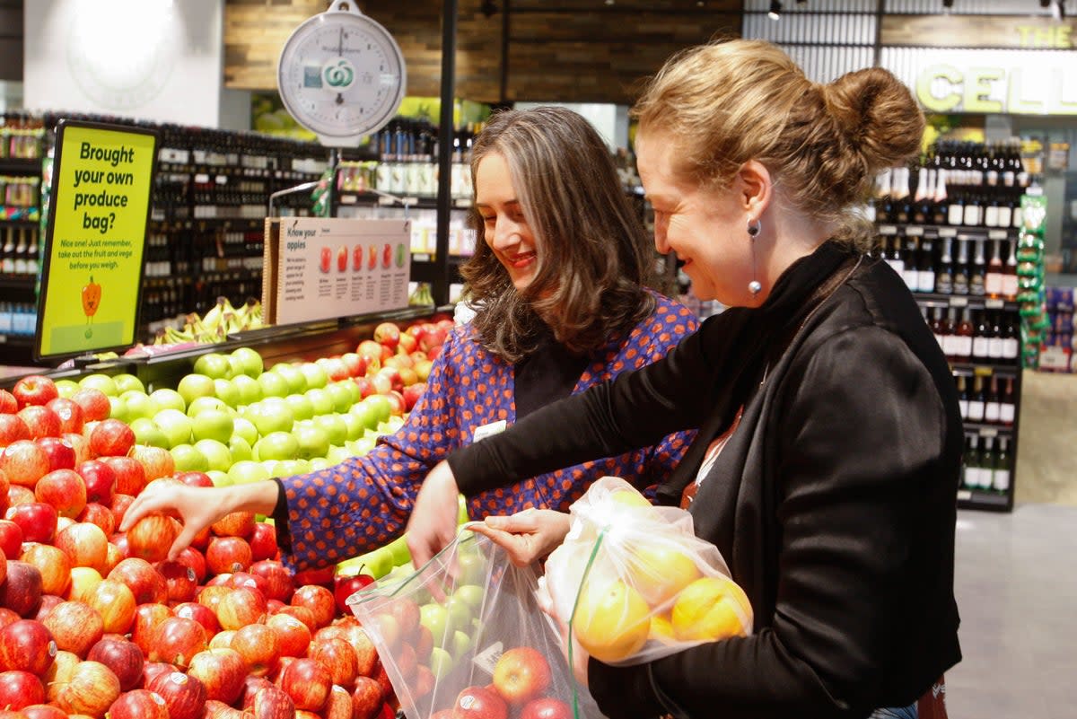 Catherine Langabeer, left, the head of sustainability at the Countdown chain of supermarkets, and Associate Environment Minister Rachel Brooking demonstrate collecting fruit in reusable polyester mesh bags on Thursday (AP)