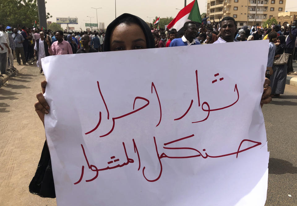 A Sudanese protester holds an Arabic placard that reads: "Free revolutionaries will continue the path," during a demonstration against the military council, in Khartoum, Sudan, Sunday, June 30, 2019. Tens of thousands of protesters have taken to the streets in Sudan's capital and elsewhere in the country calling for civilian rule nearly three months after the army forced out long-ruling autocrat Omar al-Bashir. The demonstrations came amid a weekslong standoff between the ruling military council and protest leaders. (AP Photo/Hussein Malla)