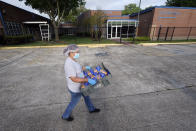 A Houston Independent School District Nutrition Services employee carries packages of buns to be distributed Monday, April 6, 2020, in Houston. HISD relaunched their food distribution efforts throughout the district Monday, with a streamlined process that will implement increased safety measures. (AP Photo/David J. Phillip)