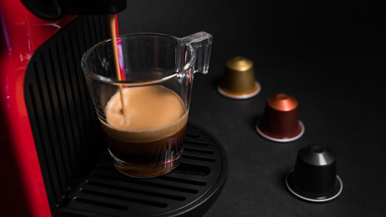 Nespresso coffee dispensing into a mug next to coffee pods