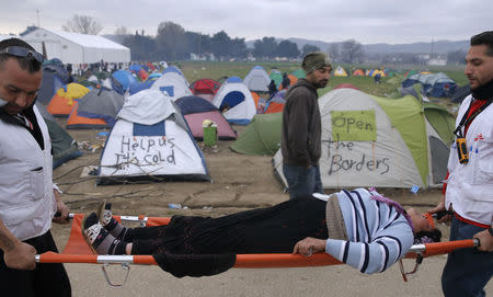 Medical volunteers carry a woman on stretcher after she collapsed, at a camp for migrants who are waiting to cross the Greek-Macedonian border near the village of Idomeni, Greece March 7, 2016. REUTERS/Marko Djurica