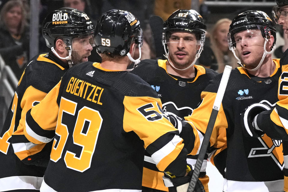 Pittsburgh Penguins' Jake Guentzel (59) celebrates with Bryan Rust, left, Sidney Crosby (87), and Chad Ruhwedel after scoring during the second period of an NHL hockey game against the Florida Panthers in Pittsburgh, Wednesday, Feb. 14, 2024. The Panthers won 5-2. (AP Photo/Gene J. Puskar)