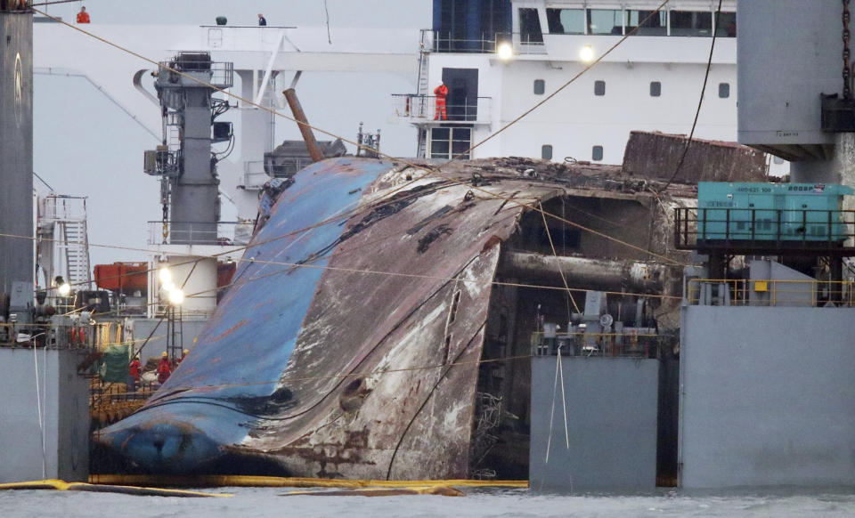 The sunken Sewol ferry is loaded onto a semi-submersible transport vessel during the salvage operation in waters off Jindo, South Korea, Saturday, March 25, 2017. Salvage crews towed the corroded 6,800-ton South Korean ferry toward a transport vessel on Friday after it was successfully raised from waters off the country's southwest coast. The massive attempt to bring the ferry back to shore, nearly three years after it sank, killing 304 people, is being closely watched by a nation that still vividly remembers the horrific accident. (Lee Jin-wook/Yonhap via AP)