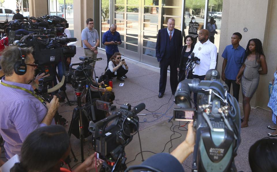 Rev. Jarrett Maupin, center, a civil rights advocate, speaks during a news conference as Dravon Ames, second from right, and Iesha Harper, right, are joined by their attorneys Sandra Slaton, second from left, and Tom Horne, left, at Phoenix City Hall, Monday, June 17, 2019, in Phoenix. Ames and his pregnant fiancée, Harper, who had guns aimed at them by Phoenix police during a response to a shoplifting report say they don't accept the apologies of the city's police chief and mayor and want the officers involved to be fired. (AP Photo/Ross D. Franklin)