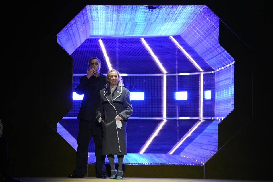 Italian designer Miuccia Prada, right, flanked by c0 designer Raf Simons, acknowledges the applauses at the end of her Prada men's Fall-Winter 2022-23 collection, unveiled during the Fashion Week in Milan, Italy, Sunday, Jan. 16, 2022. (AP Photo/Luca Bruno)