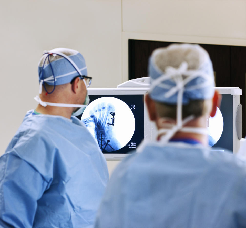 Two surgeons in a hospital operating room examining X-ray images on a screen