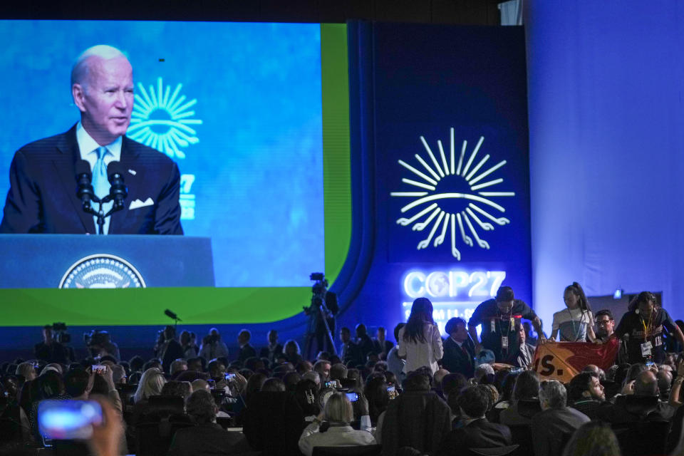 President Joe Biden speaks as protesters have a banner removed by security, bottom right, at the COP27 U.N. Climate Summit, Friday, Nov. 11, 2022, in Sharm el-Sheikh, Egypt. (AP Photo/Peter Dejong)