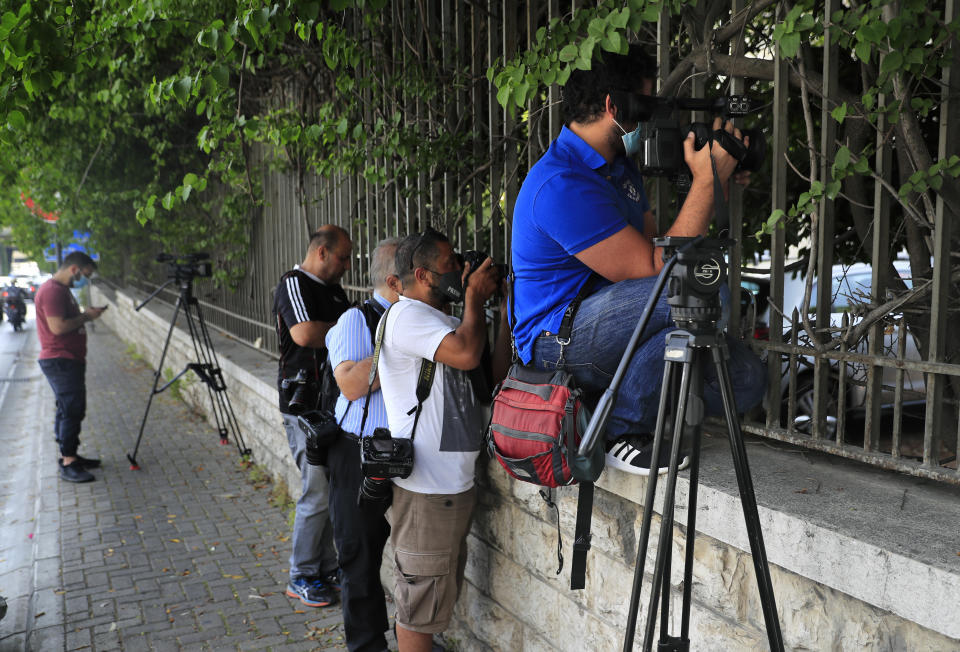 Lebanese photographers take pictures through the fence of the Justice palace, where former Nissan executive Carlos Ghosn is being questioning, in Beirut, Lebanon, Monday, May 31, 2021. Lebanese judicial officials say a team of French investigators has begun questioning Ghosn over suspicions of financial misconduct. (AP Photo/Hussein Malla)