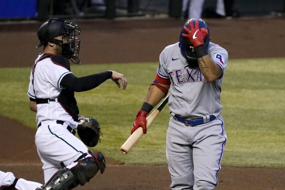 Texas Rangers' Rougned Odor, right, walks back to the dugout after striking out as Arizona Diamondbacks catcher Carson Kelly, left, throws the ball back the pitcher during the first inning of a baseball game Tuesday, Sept. 22, 2020, in Phoenix. (AP Photo/Ross D. Franklin)