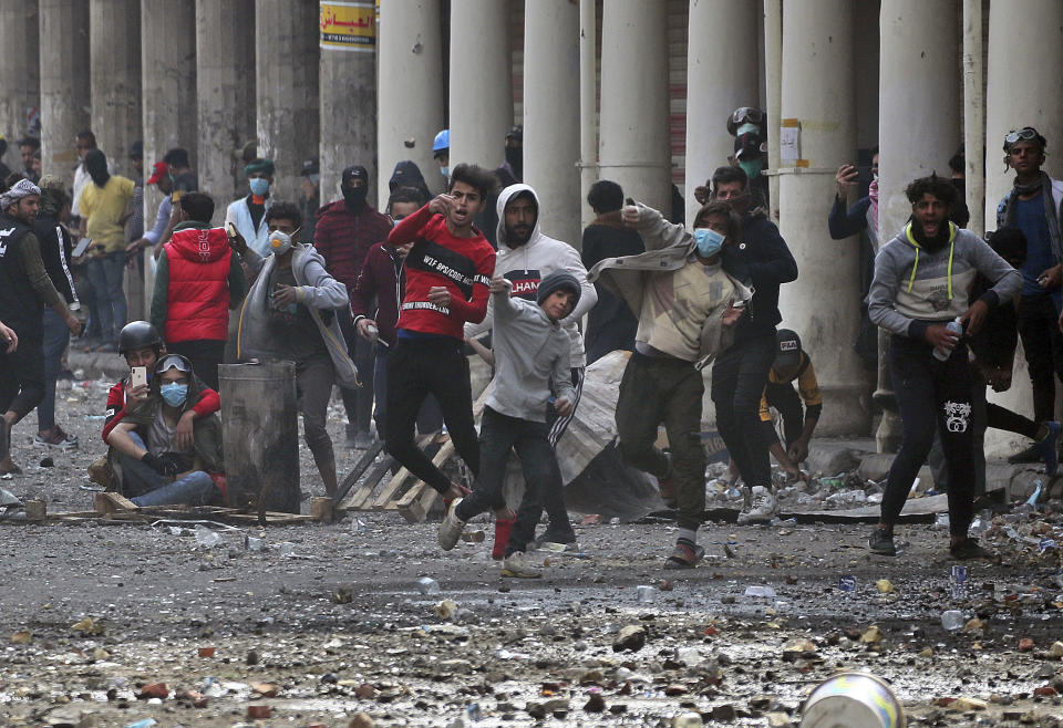 Protesters throw stones at riot police during clashes between Iraqi security forces and anti-government protesters in Baghdad, Iraq, Saturday, Nov. 23, 2019. (AP Photo/Hadi Mizban)